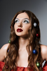 Fototapeta premium Brightly adorned young woman showcases artistic makeup and hairstyle while embracing the festive winter spirit.