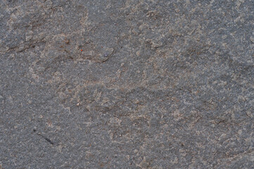 Close up of a textured grey and brown stone surface with fine granular details providing a natural abstract background for design projects