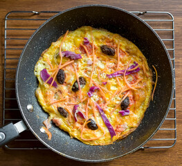 Top Shot of Ham, Cheddar Cheese, Cabbage, Carrots and Kalamata Olives Frittata Omelette in Frying Pan