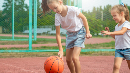the two girl child playing basketball game on sport court