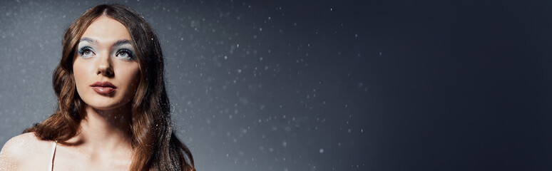 A beautiful young woman strikes a pose as snow gently falls around her, banner