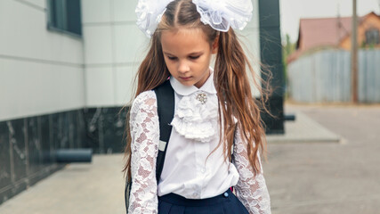 Close up portrait of happy cute junior girl smiling to camera while standing outdoor at schoolyard....