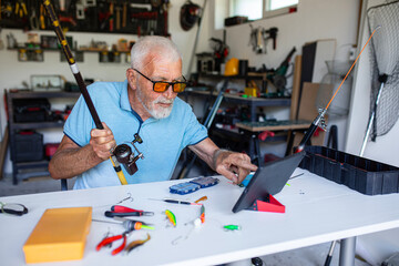 Elderly fisherman watching instructions on a tablet to set up his fishing gear