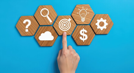 Strategic Business Planning Concept with Wooden Hexagons Displaying Question, Search, Target, Idea, Money, Cloud, and Gear Icons on a Vibrant Blue Background