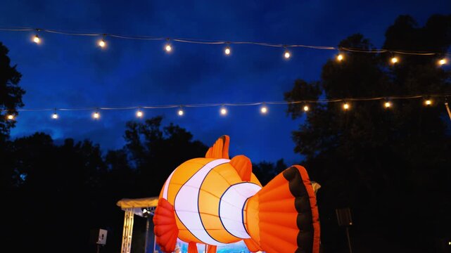 The Giant Lantern Fish shines bright at Night, surrounded by twinkling lights that create a magical atmosphere