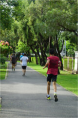 Fresh green lawns in the park. Blur nature bokeh green park trees in morning. People jogging in the morning.