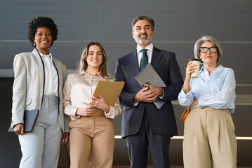 Diverse group of business professionals standing together in a modern office, representing teamwork, diversity, and success in the corporate world