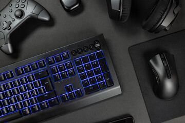 Blue lit keyboard surrounded by various modern wireless gadgets