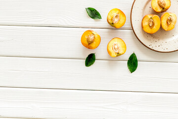 Healthy food. Ripe sliced peaches on plate on white wooden table top-down copy space