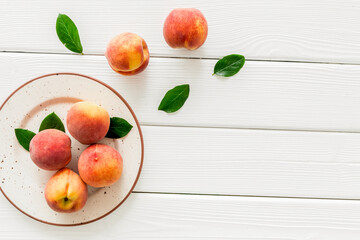Summer fruits. Ripe red peaches on plate on white wooden table top-down copy space