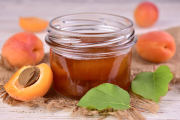 Apricot jam in a jar and fresh apricots on the table. Close-up.
