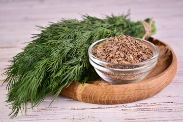Fresh dill and dill seeds on white wooden background. Close-up.
