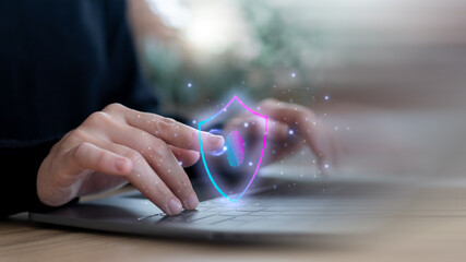 Hand using a laptop with fingerprint authentication and shield icon representing cybersecurity, data protection, privacy, online banking security, and digital identity verification concept.