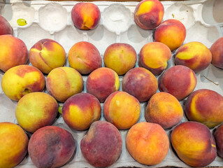 Colorful stone fruits including peaches and plums arranged in abundant summer fruit display at local market stand. high quality photograph