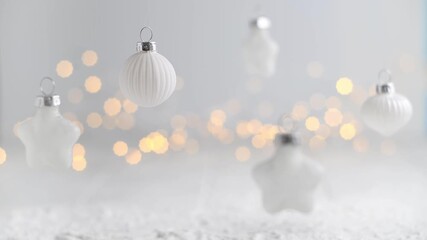 White christmas ornaments of various shapes hanging against a light background with soft, warm bokeh from sparkling lights, evoking a serene and festive holiday mood - Powered by Adobe