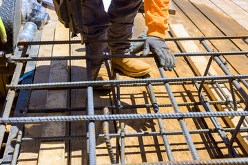Fototapeta premium Construction worker assembling metal rebar grid framework for building, under construction work day
