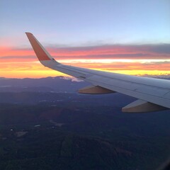 Obraz premium Airplane wing over a colorful sunrise