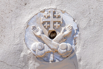The Jerusalem Cross or Crusader Cross with two hands on each side of the cross representing Jesus and St. Francis of Assisi carved in stone on Saint John's Baptist Church in the old city of Acre, Akko