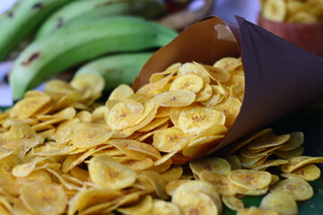 Golden plantain chips spill from paper cone. Crunchy Kerala snack, perfect for comfort and tradition