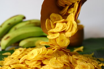 Golden plantain chips spill from paper cone. Crunchy Kerala snack, perfect for comfort and tradition