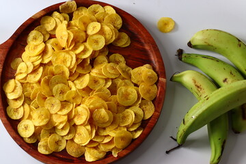 Plantain chips on wooden plate with raw plantains, South Indian snack evoking comfort and tradition