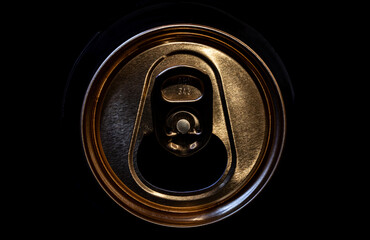 The focus is on the golden metallic surface and the intricate details of the pull tab.