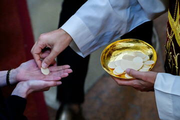 Obraz premium Priester legt Hostie in die geöffneten Hände