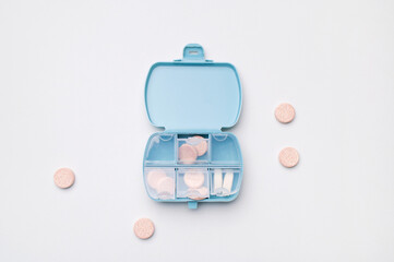 Medical pharmaceutical concept, health and beauty. Blue pill organizer, pillbox with different vitamins, capsules, tablets, pills, dietary supplements on gray background flat lay top view