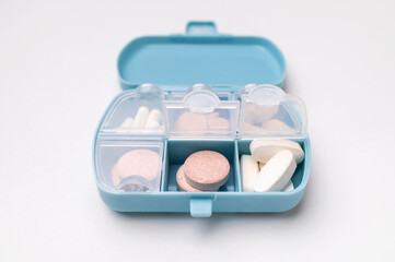Medical pharmaceutical concept, health and beauty. Blue pill organizer, pillbox with different vitamins, capsules, tablets, pills, dietary supplements on gray background flat lay top view