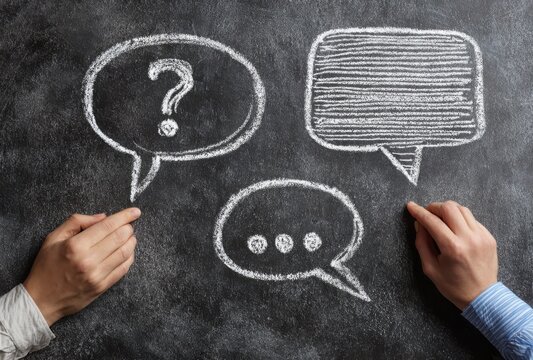 Two hands pointing at chalk drawings of speech bubbles on a blackboard, one with a question mark