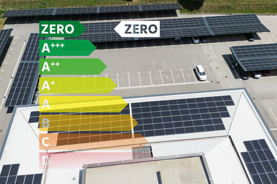 Aerial view of building with solar panels on a roof and parking space with solar canopies