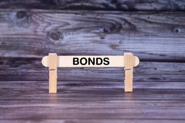 Bonds symbol. A wooden stick secured by Clothespins set over beautiful Realistic Wooden Texture Background. Business and Bonds concept with copy space