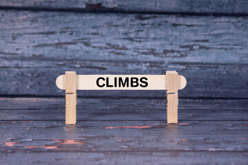 Climbs symbol. Wooden stick fastened by Clothespins, A lightly orange toned grunge wooden background. Business and Climbs concept with copy space