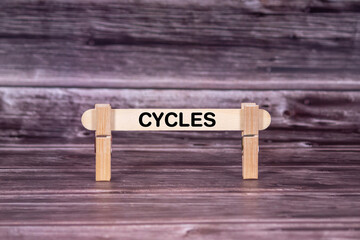Cycles symbol. Wooden stick held by Clothespins, beautiful Realistic Grunge Wooden Background. Business and Cycles concept with copy space