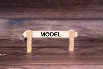 Model symbol. Clothespins gripping a wooden stick against a beautiful Brown Wooden Background . Business and Model concept with copy space