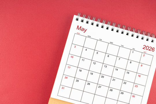 May 2026 desk calendar on red color background. Flat lay.