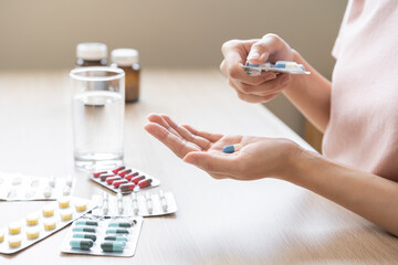 Sick ill asian young woman, girl hand taking tablet pill capsule out from blister pack, painkiller...