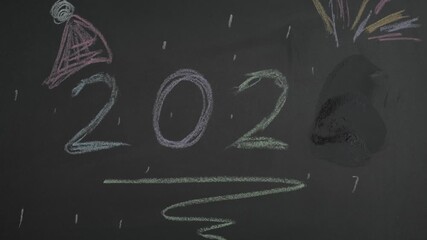 Wipe off 2025 and writing number 2026 on a blackboard using chalk 