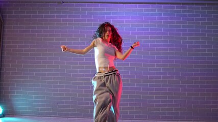 young girl choreographer dancing hip hop in neon lighting, woman performing on camera in and practicing dance jazz funk in dark studio - Powered by Adobe