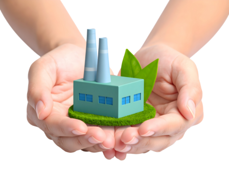 Hands gently hold a miniature green factory with leaves, symbolizing sustainable industry and environmental care.