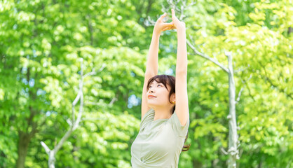 緑の中でストレッチをする女性