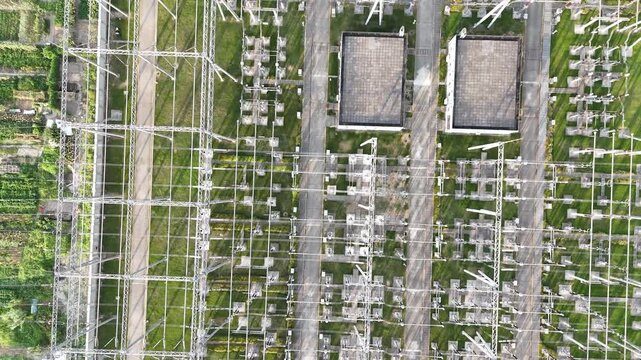 Aerial drone view of a modern power substation with symmetrical grid patterns and green spaces, illustrating sustainable energy infrastructure and the transition to clean electricity.