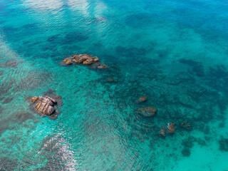 Seychelles aerial view, Praslin Island. Granite rock formations along a tropical shoreline with transparent turquoise waters and lush coastal vegetation. Exotic landscape.