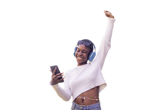 Joyful woman with headphones and phone celebrates with raised arm