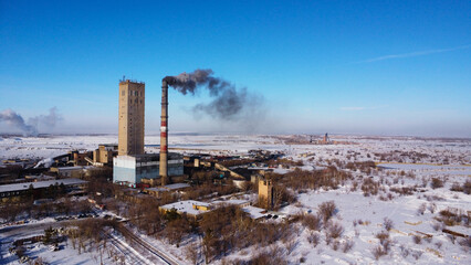 smoking factory and its towers in a vast winter landscape