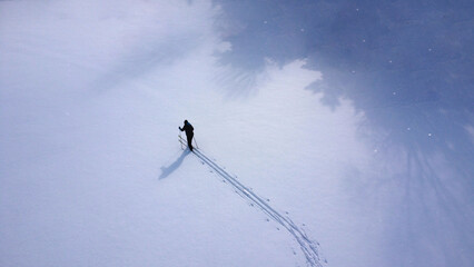 A lone skier trekking across a vast, snowy landscape