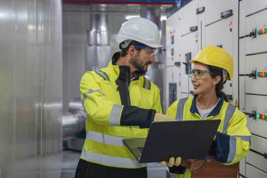 Foreman and Engineer Plan System Upgrade Construction foreman and engineering manager discussing plans while examining the existing industrial air conditioning system