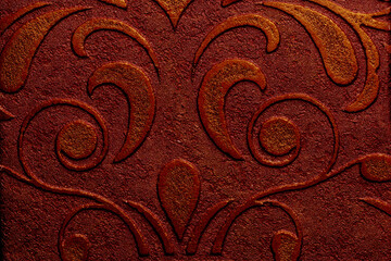 Dark red wallpaper with decorative plaster texture featuring a pattern of floral scrolls and leaves for apartment interior design