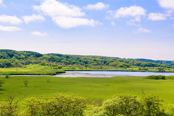 Obraz premium A brackish lagoon called Poroto-numa located within the Poroto Marsh in Hamanaka, Hokkaido, Japan. The lagoon is surrounded by wetlands and aquatic plants, creating a serene natural landscape under a 
