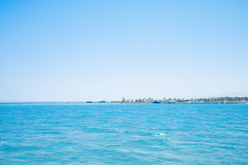 Clear blue ocean with distant palm trees